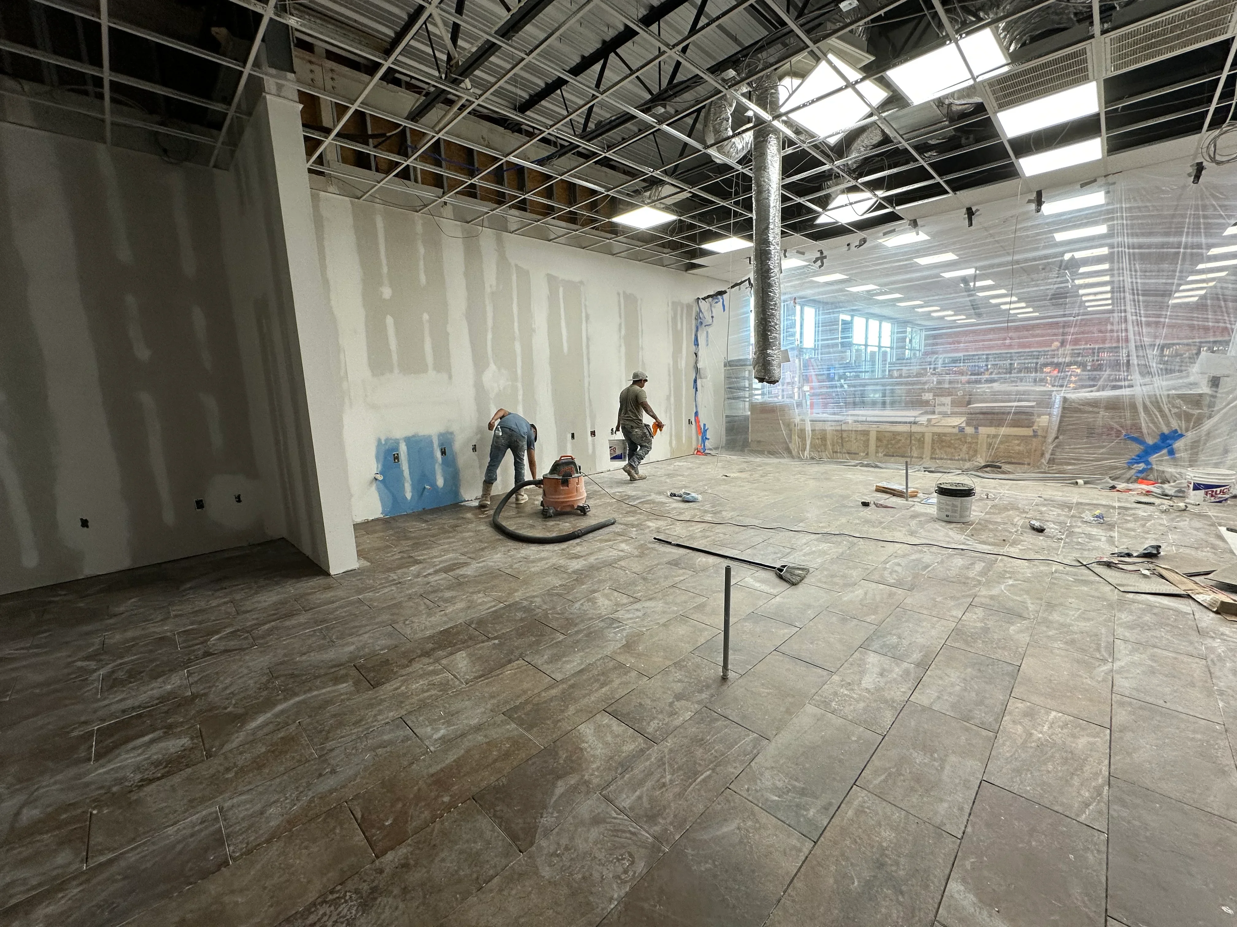 Drywall partitions, wood-look tile flooring, metal framing in commercial interior space