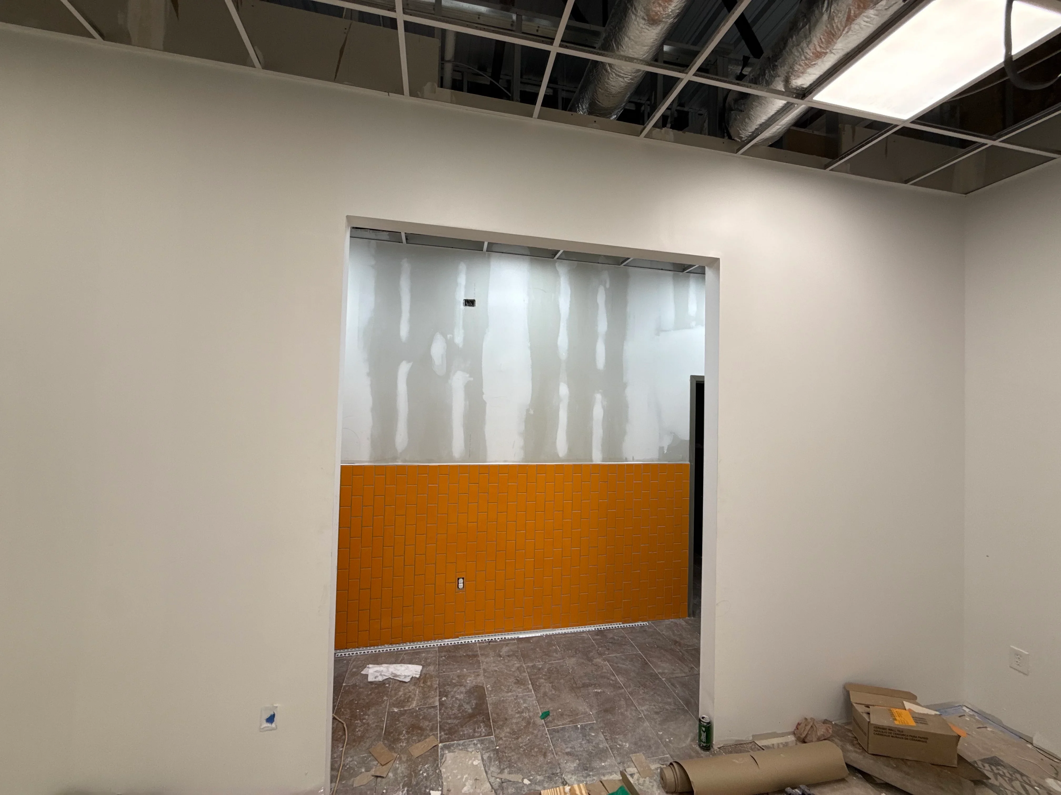 Glass and orange tile partition wall with frosted panels and ceramic tile base in commercial interior