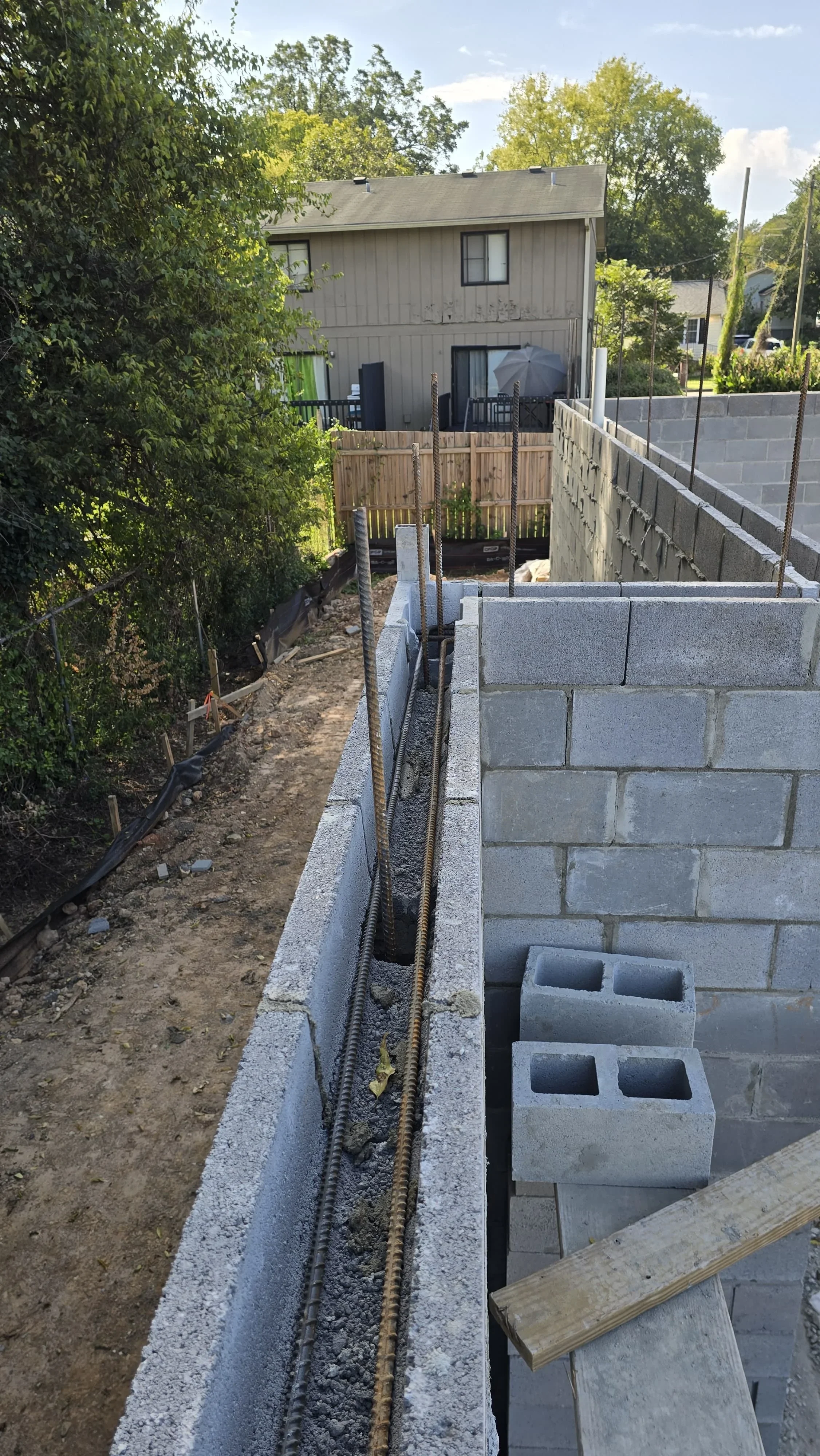 Concrete block retaining wall with drainage pipe and gravel base during construction