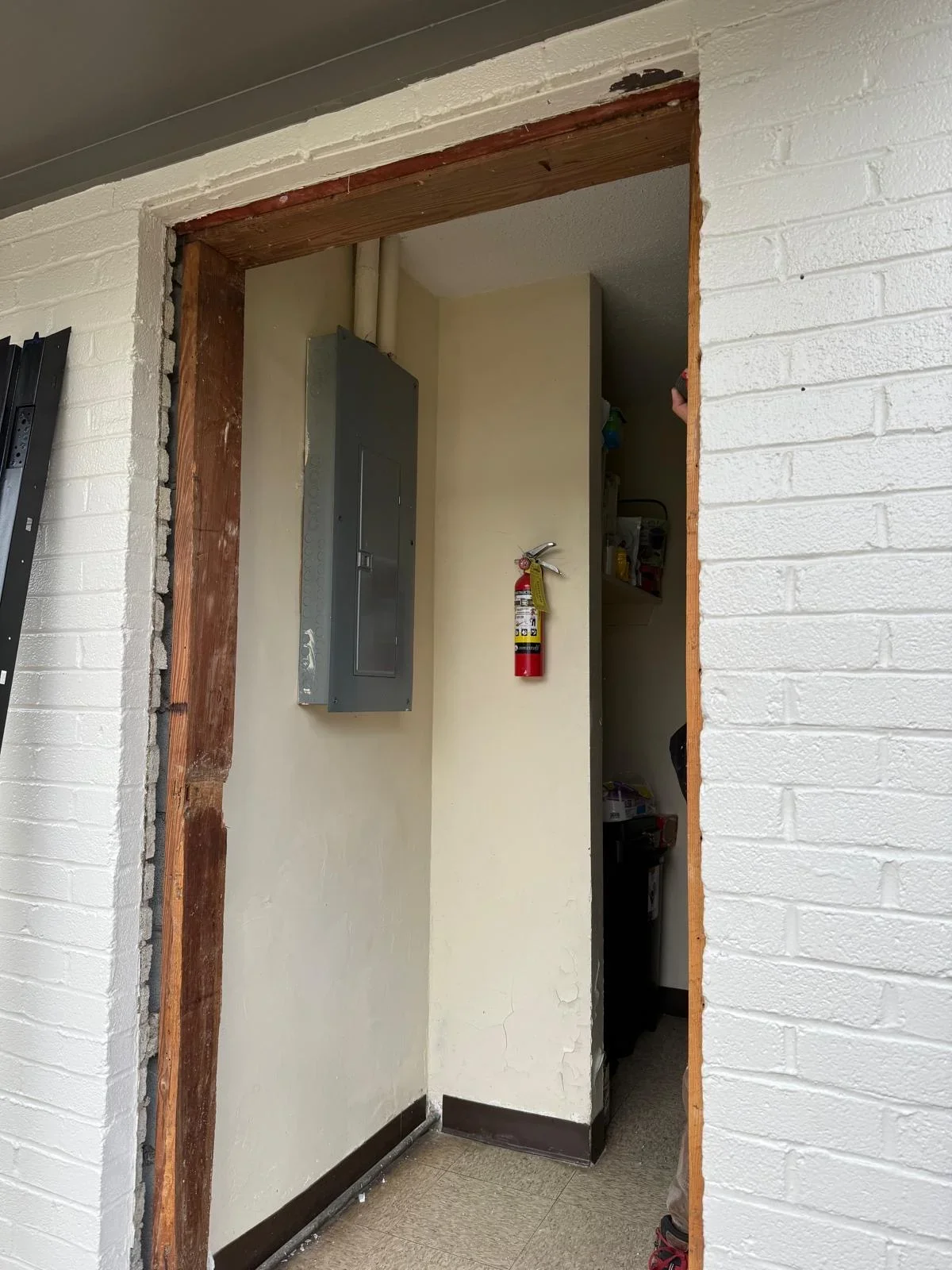 Wood-framed doorway opening with drywall jambs and white painted walls in brick structure