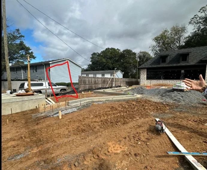 Excavated residential lot with concrete foundation, PVC utilities, and framing materials