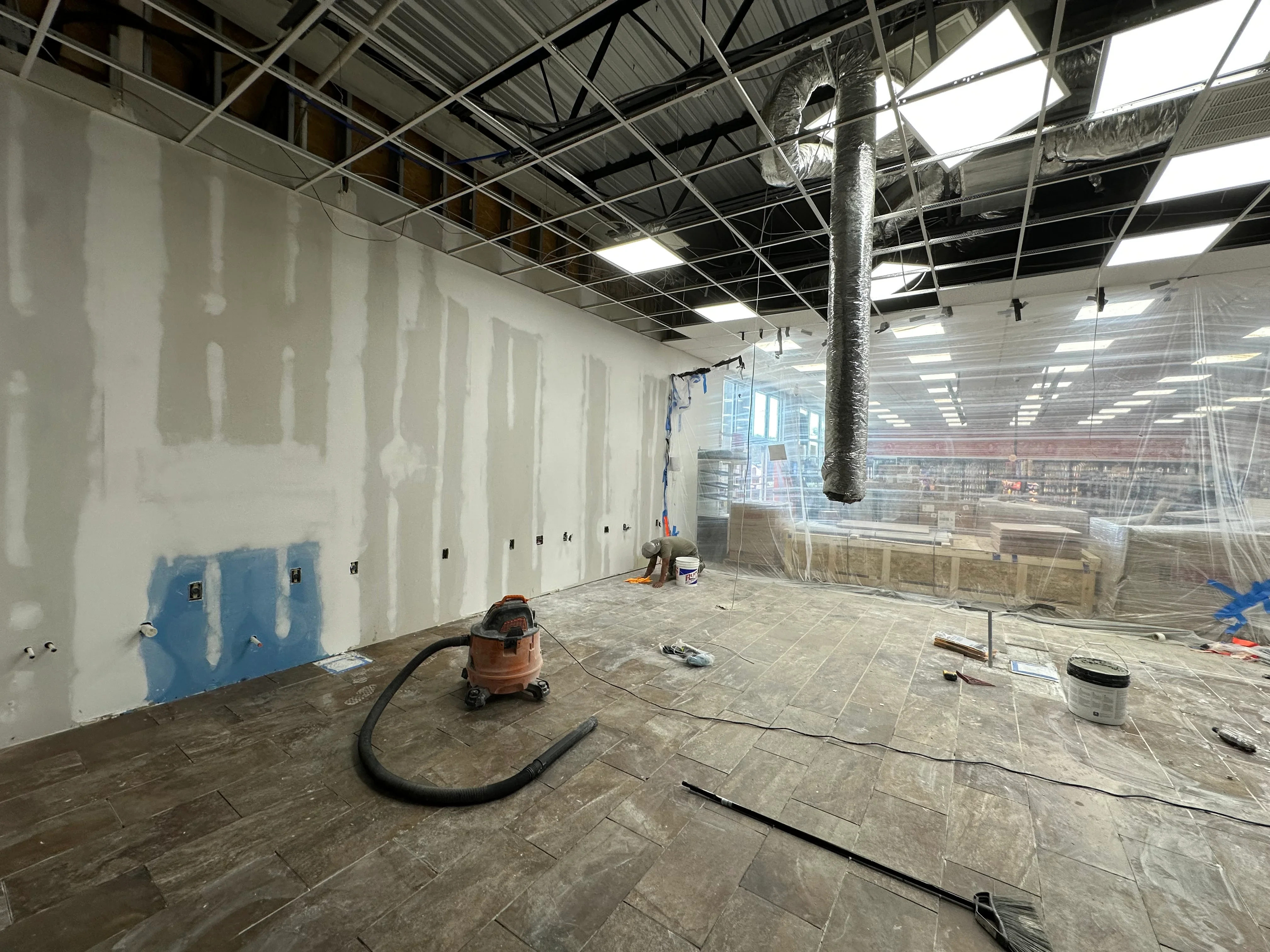 Drywall installation in commercial space with mudded joints, electrical boxes, and concrete flooring