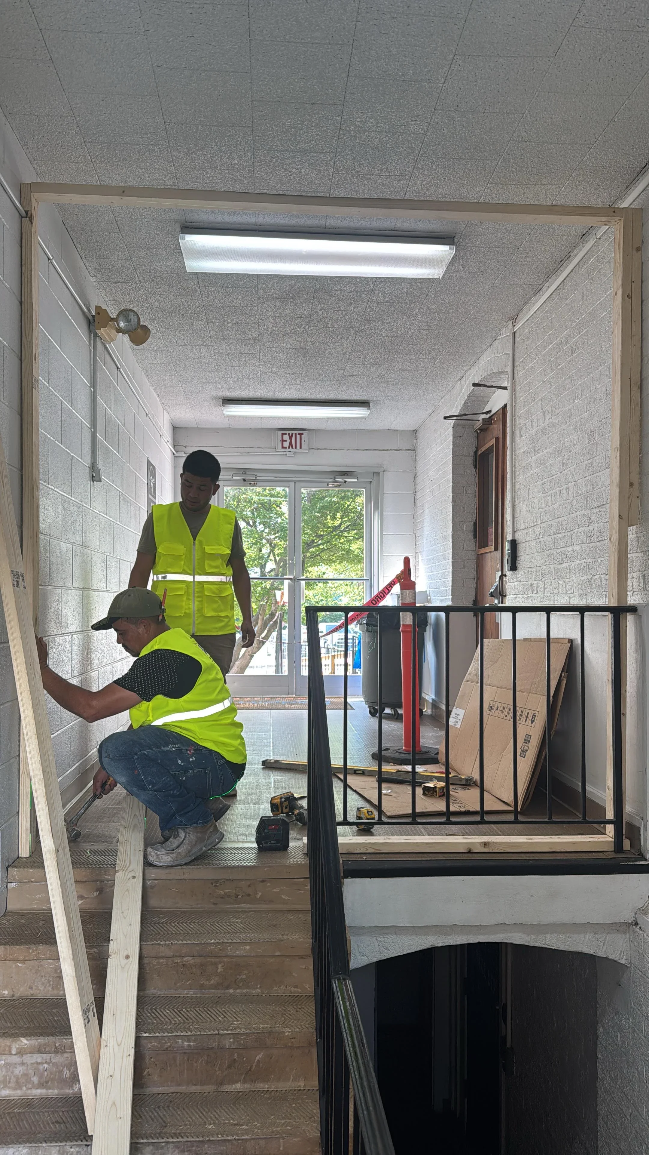 Workers installing white painted brick walls and lighting in commercial hallway renovation