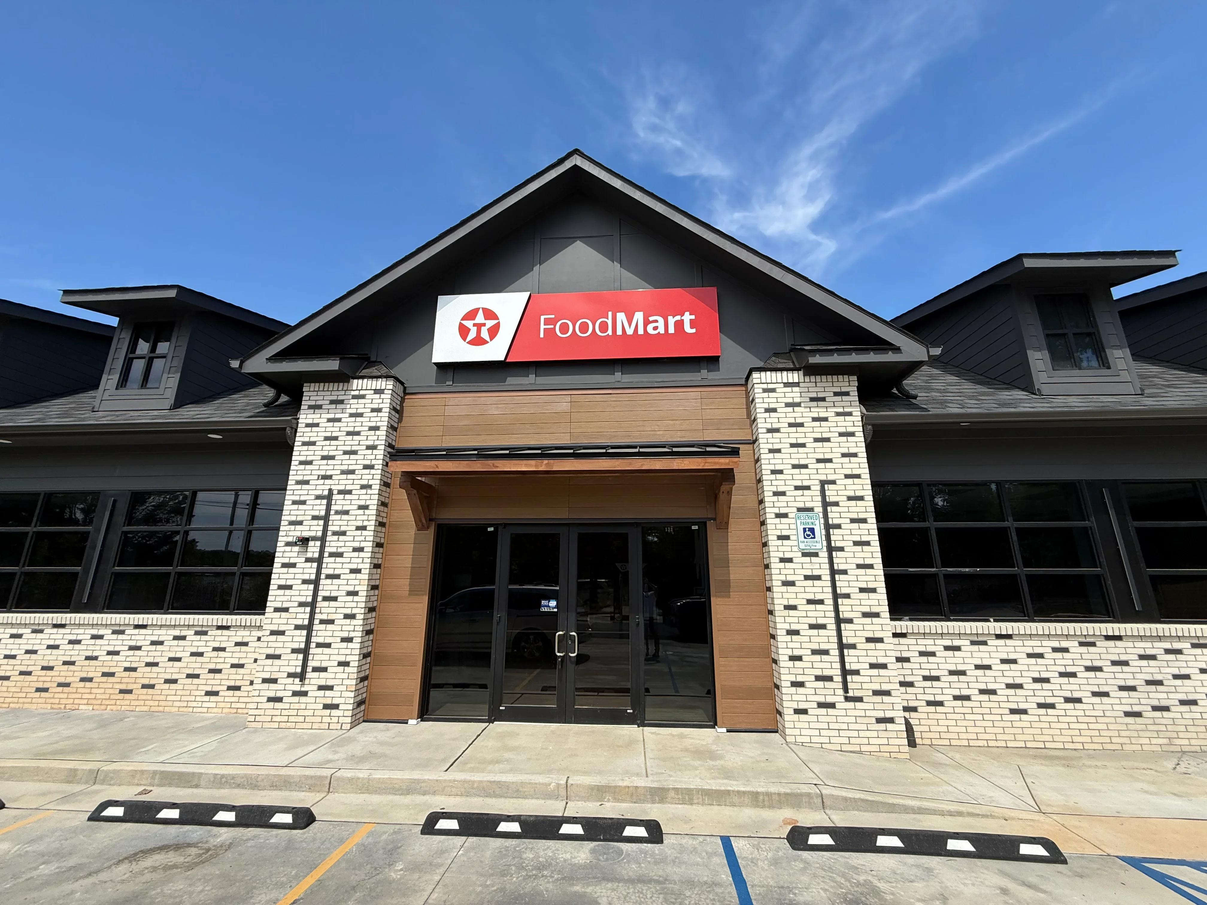 Retail storefront with cream brick, wood cladding, and glass entry doors