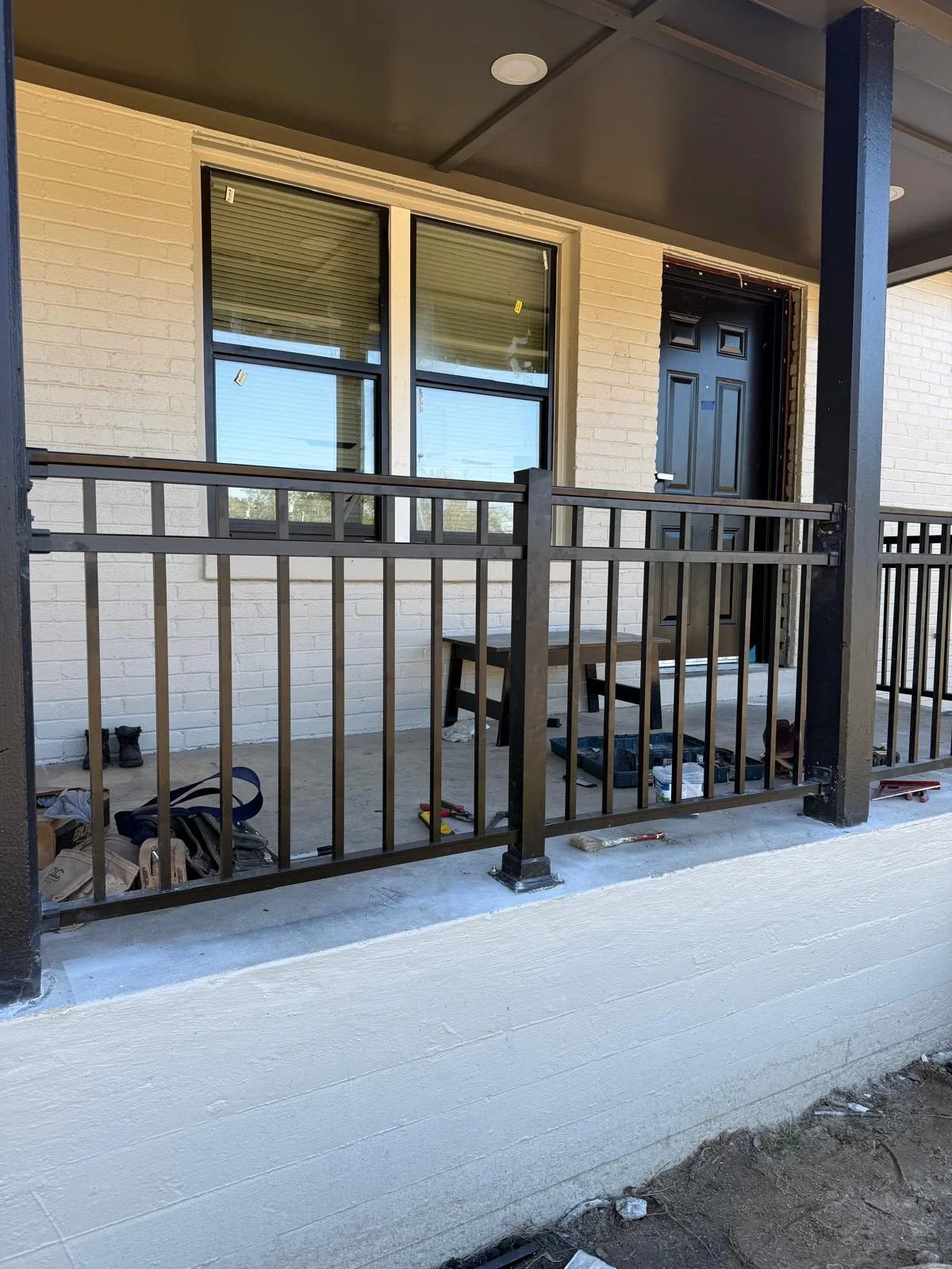 Black metal porch railing with vertical pickets on white brick residential entry