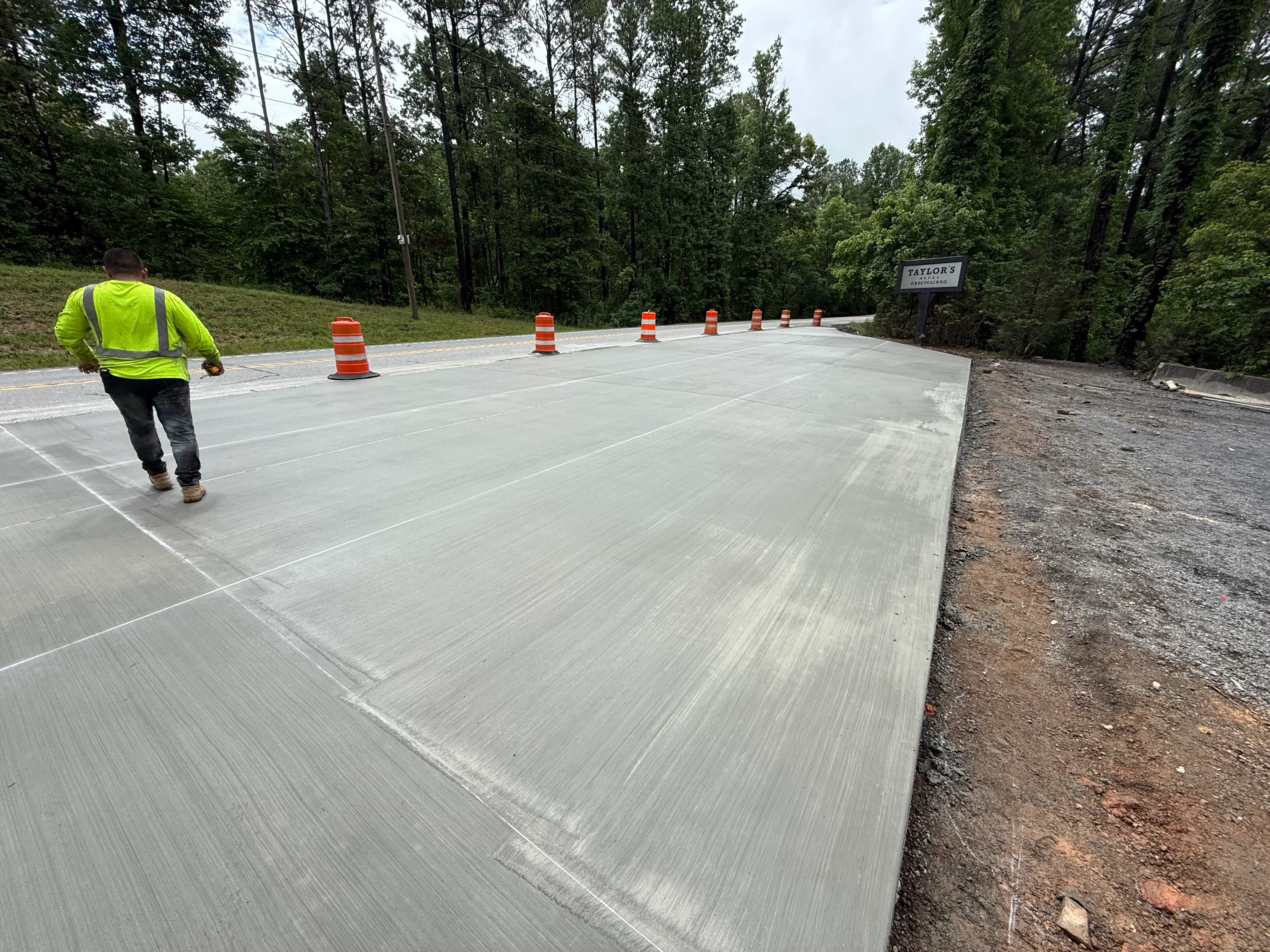 Freshly poured concrete driveway with control joints and traffic cones during curing phase