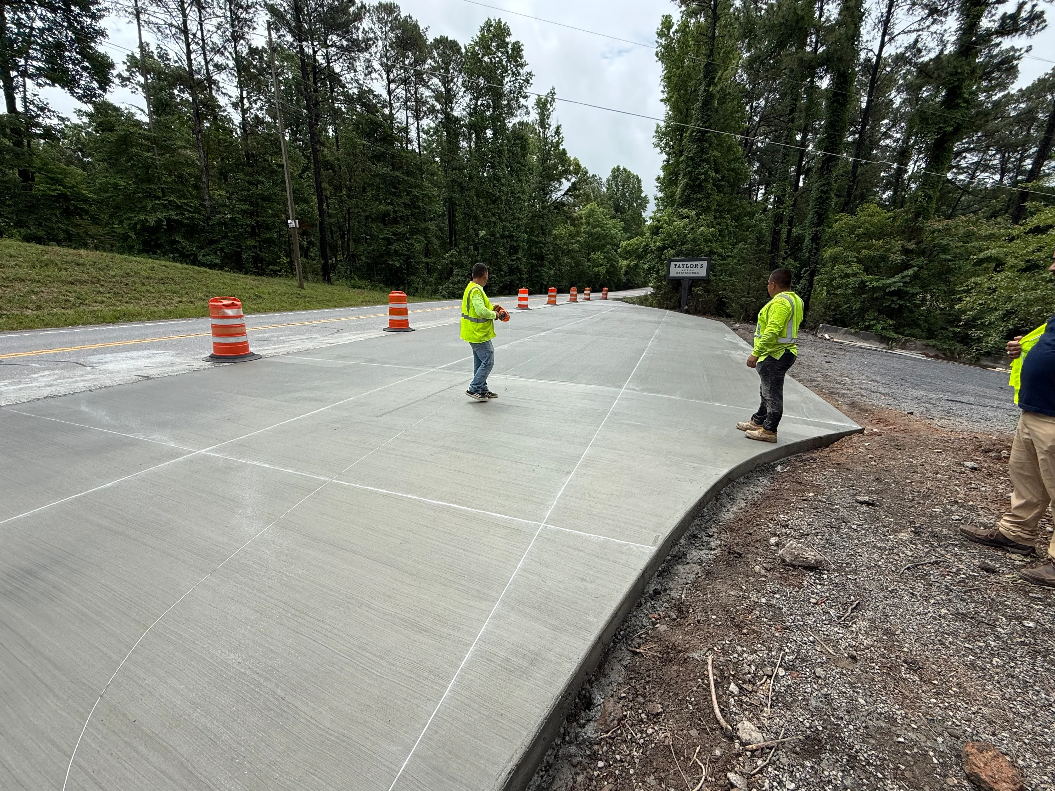 Freshly poured concrete driveway with control joints and traffic cones during curing phase
