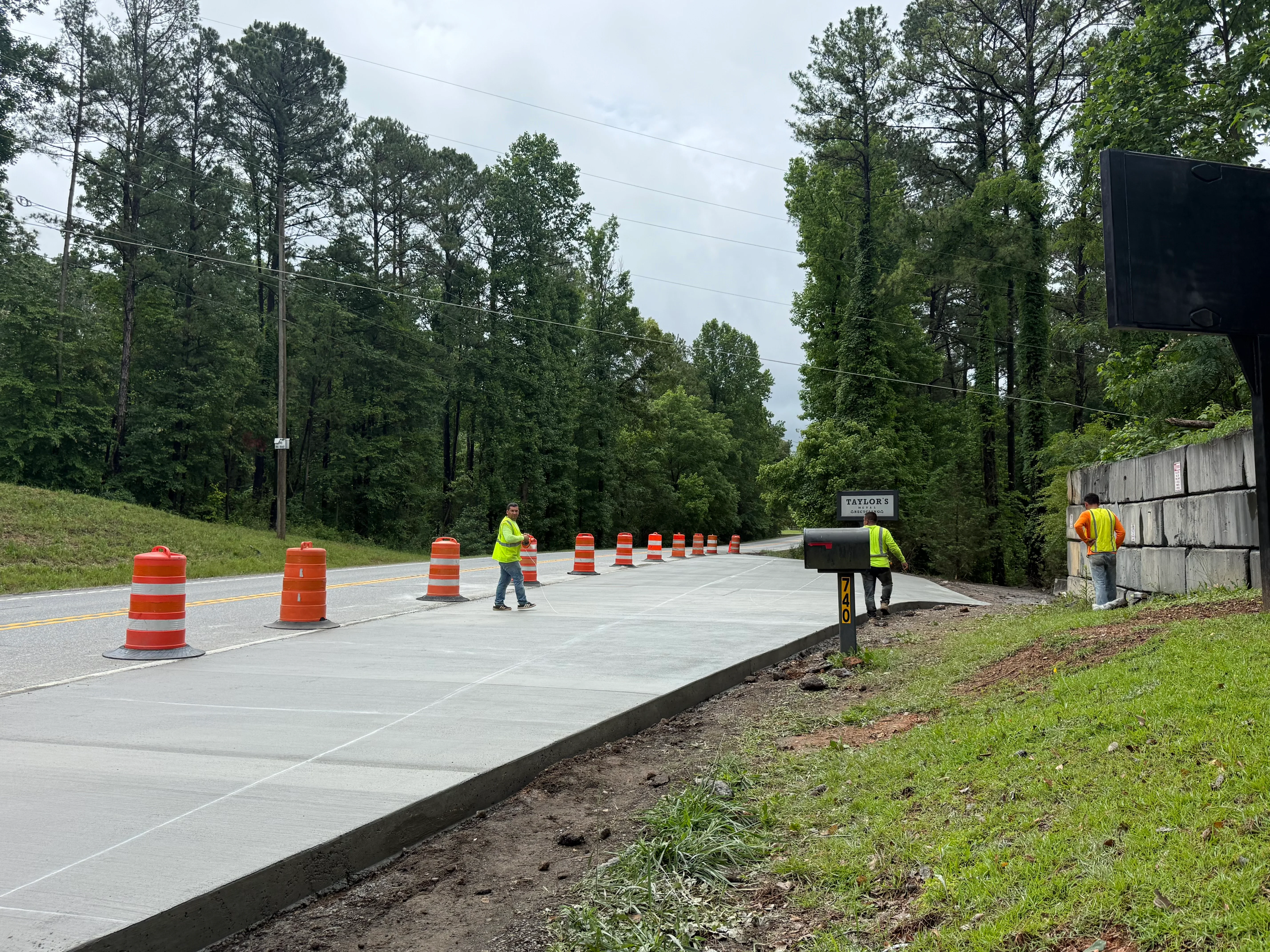 New concrete driveway with control joints, traffic cones, and safety barriers during construction