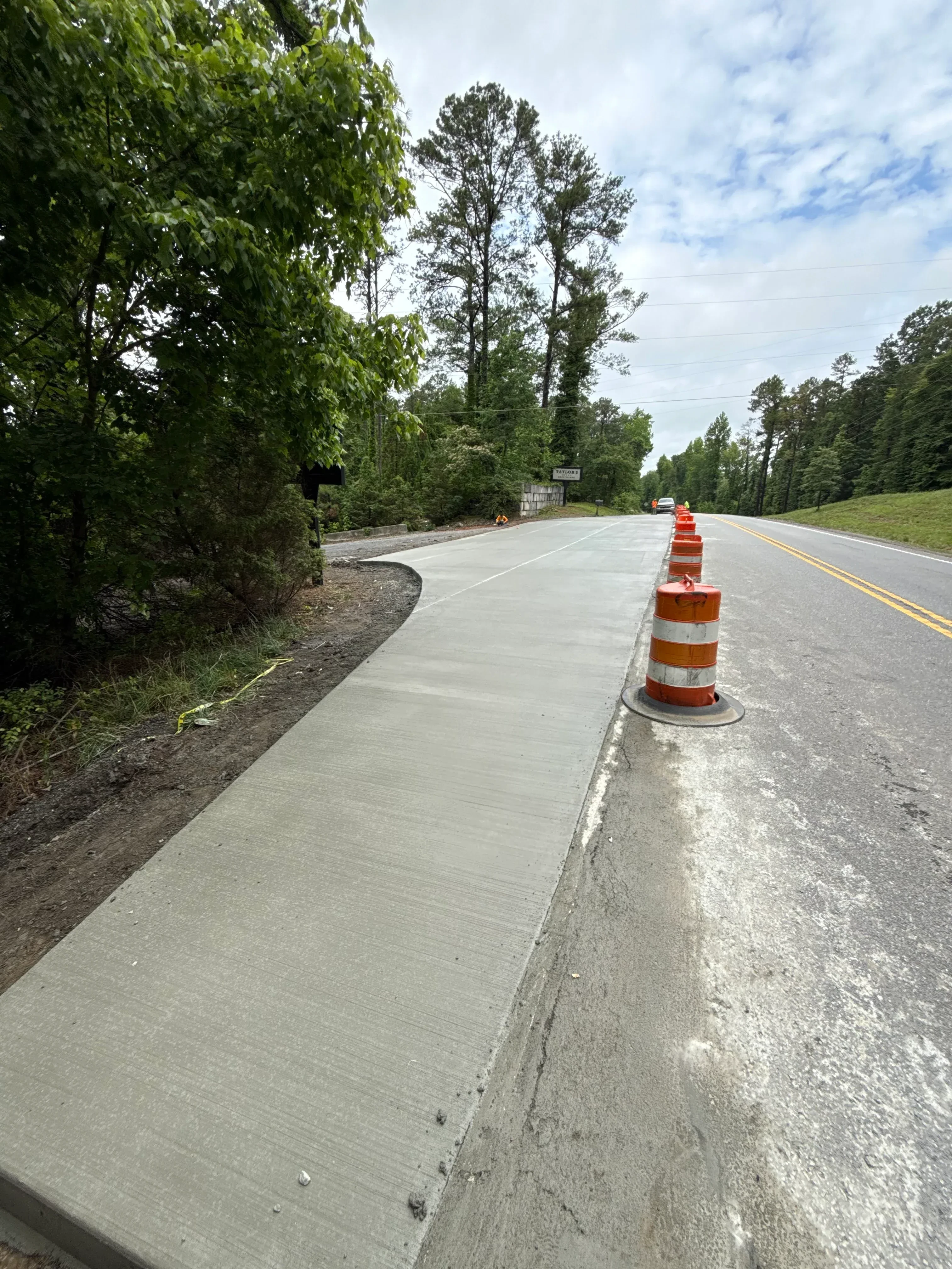 Newly paved asphalt driveway with yellow center line and traffic control cone