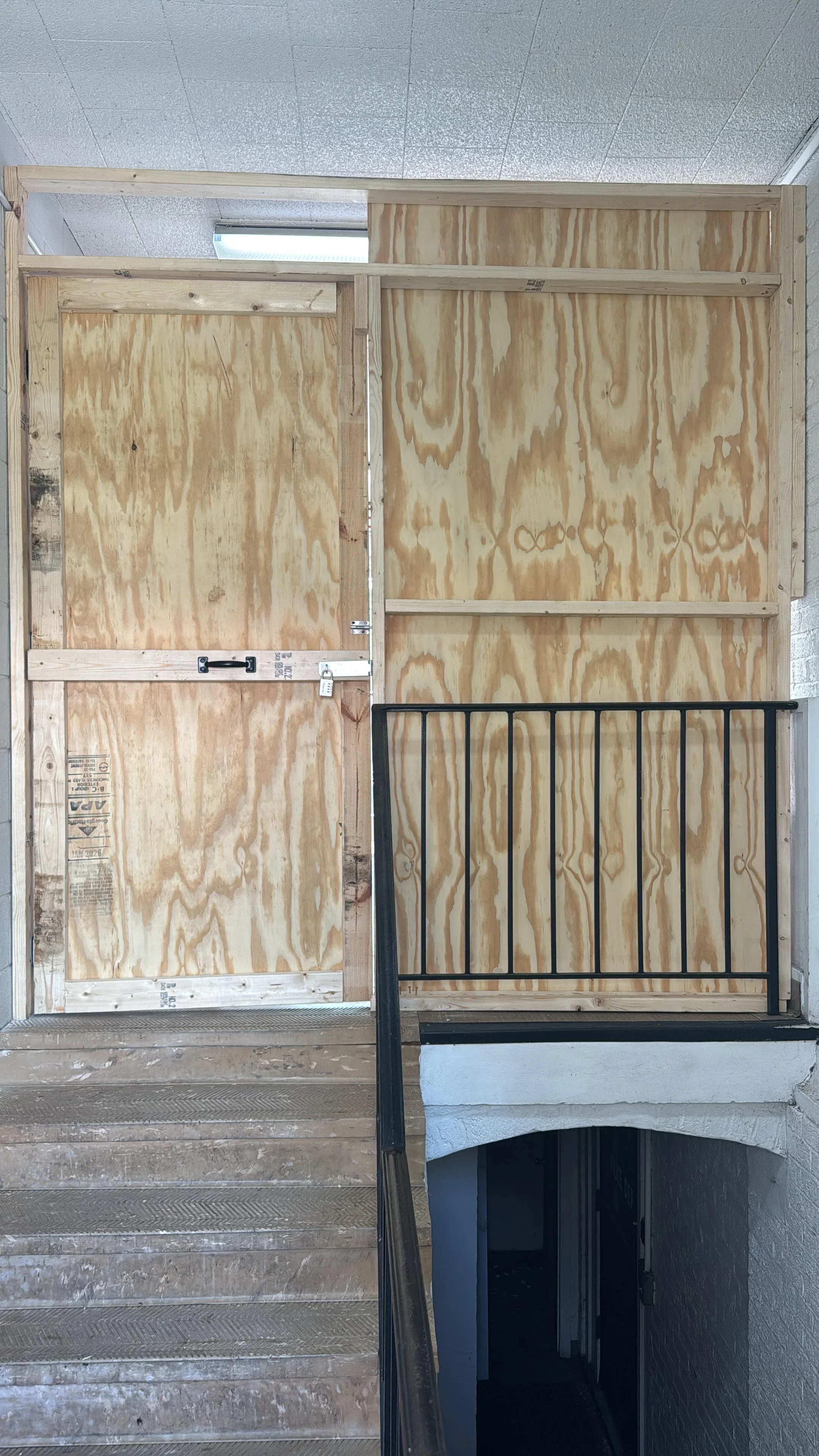 Plywood-framed horse stalls with black metal gate and lumber framing in indoor facility