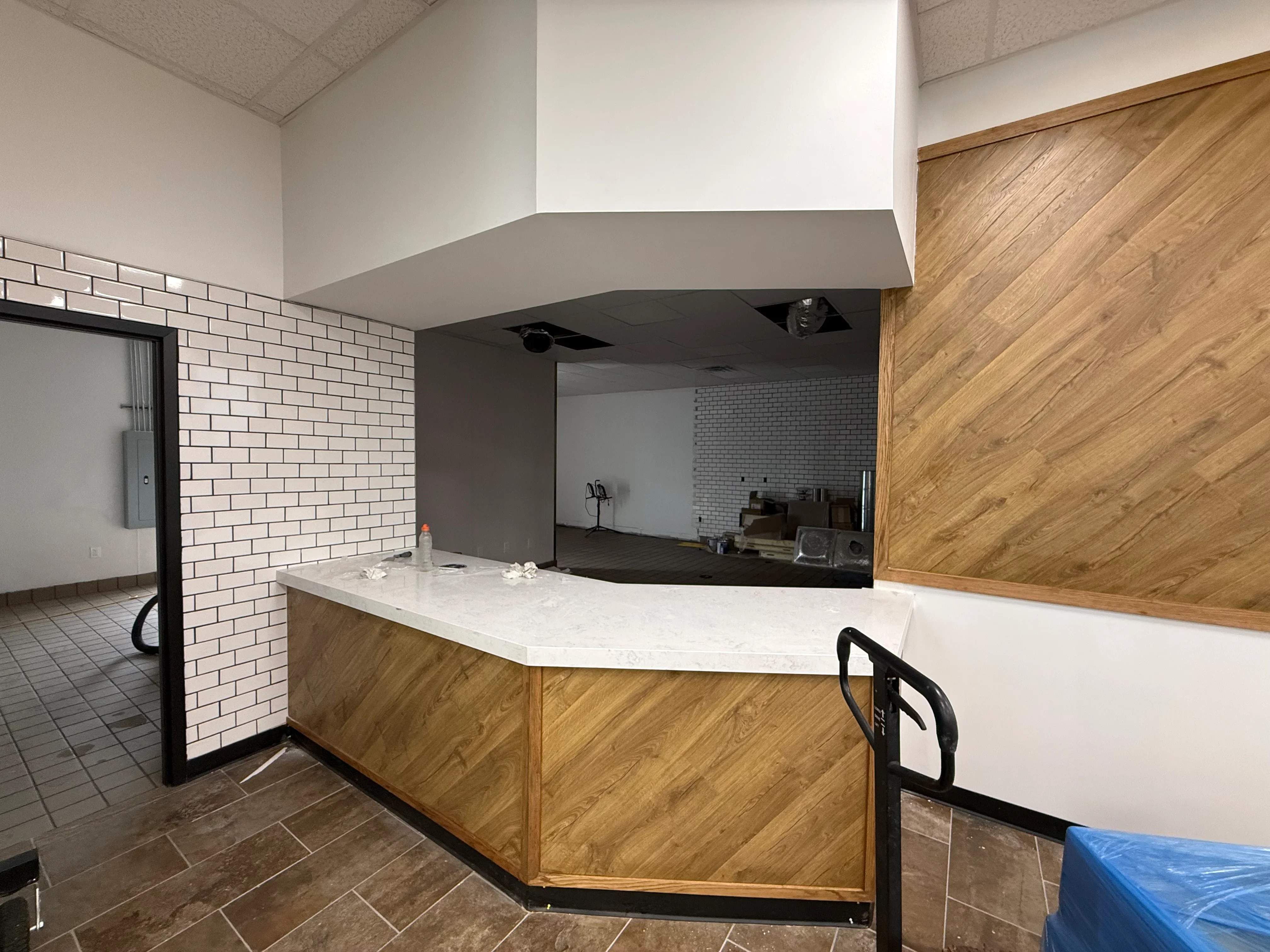 Commercial interior with wood cabinetry, marble countertop, white brick wall, and curved drywall soffit