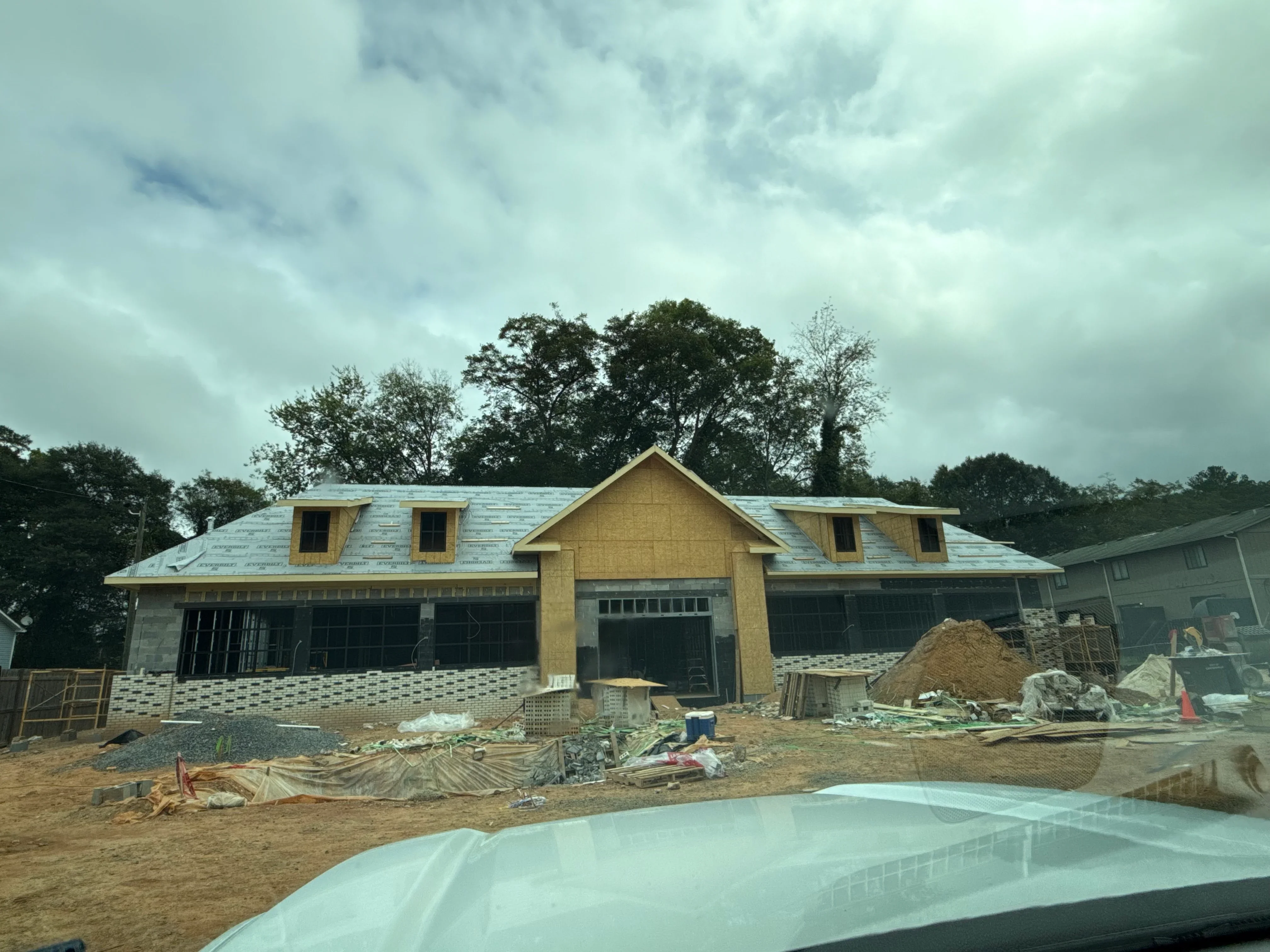 New home construction with brick, stone, and yellow siding exterior, dormers, and pitched roof during framing phase